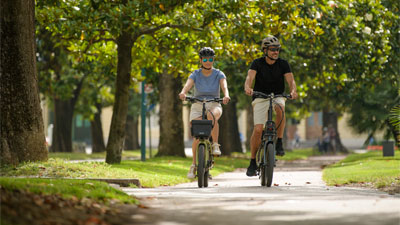 Una coppia attraversa un parco con le biciclette pieghevoli Cube.