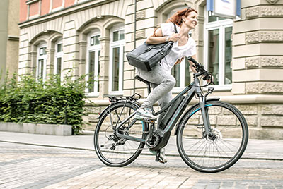 Una donna attraversa il centro città con una borsa sotto il braccio, in sella a una bicicletta Winora.