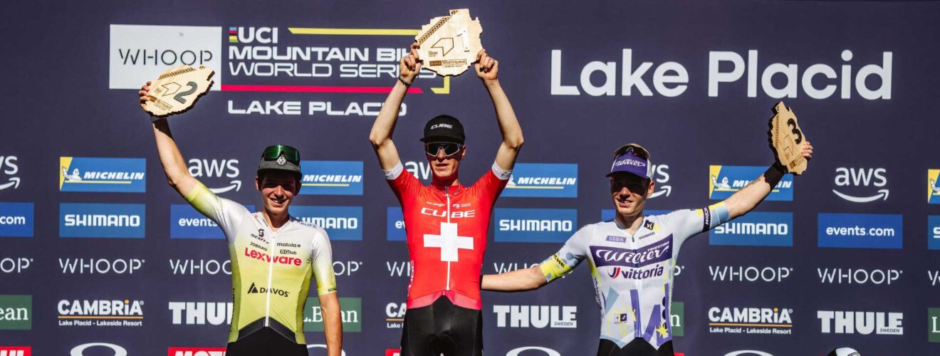 Finn Treudler esulta sul podio, alzando con orgoglio il trofeo per il suo trionfo nella categoria U23 a Lake Placid.